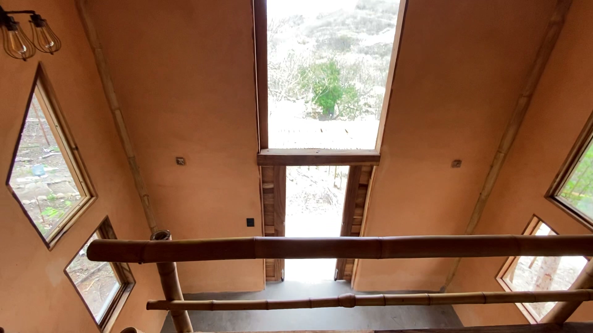 Interior de La Casita del Cerro: techo a dos aguas con estructura de bambú y muros de tierra